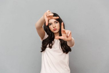 Sen fotoğraf çekme gri arka plan duvar üzerinde izole gibi elleriyle işaret bir atış almak duygusal genç bayan fotoğraf.