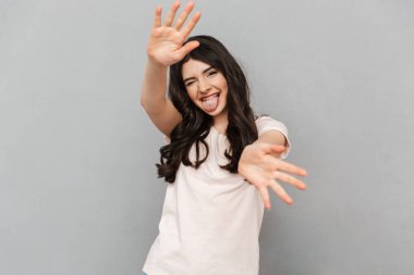 Sevimli güzel genç bayan için sallayarak gri arka plan duvar üzerinde izole ayakta görüntüsünü.