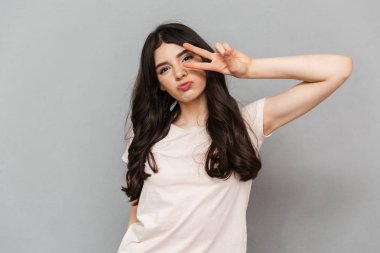 Çok hoş genç bayan barış hareketi gösterilen gri arka plan duvardan izole ayakta fotoğrafı.