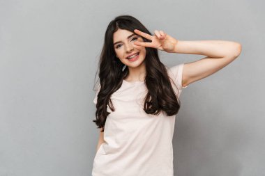 Çok hoş genç bayan barış hareketi gösterilen gri arka plan duvardan izole ayakta fotoğrafı.