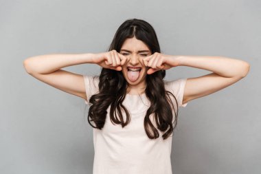 Sevimli güzel genç bayan gri arka plan duvar çığlık içinde izole ayakta fotoğrafı.