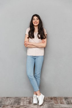 Sevimli güzel genç bayan gri arka plan duvardan izole ayakta görüntüsünü.