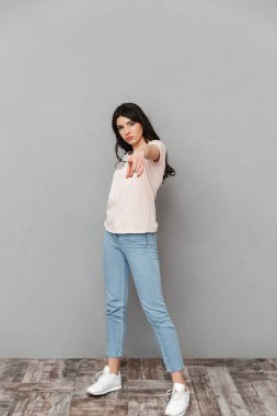 Güzel genç bayan için işaret gri arka plan duvar üzerinde izole ayakta görüntüsünü.