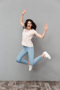 Görüntü gri arka plan duvar izole duygusal genç bayanın atlama.