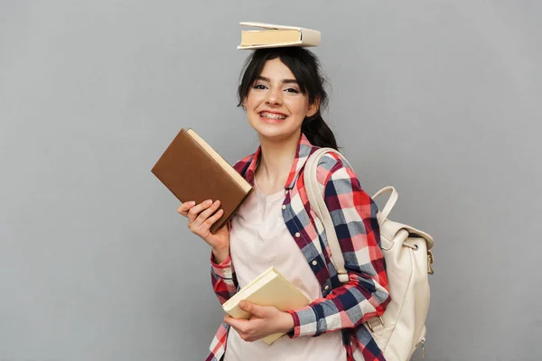 幸せな若い女性学生の分離に立って本を保持している灰色の背景の壁のイメージ — ストック写真