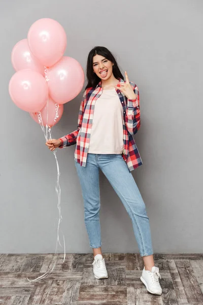 Rock jest yapmak imge-in sevimli güzel genç bayan balon tutan gri arka plan duvardan izole.
