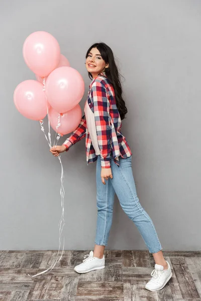 Sevimli güzel genç bayan balon tutan gri arka plan duvardan izole görüntüsünü.