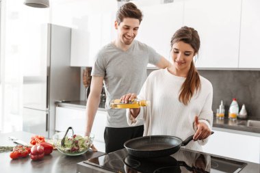 Portre çekici bir genç çiftin ile birlikte tavada mutfak, yemek