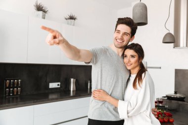 Sarılma ve uzak duran evde mutfak at işaret mutlu bir genç çift portresi