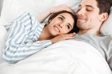 Güzel bir genç çift yan yana yatakta yatarken portresi