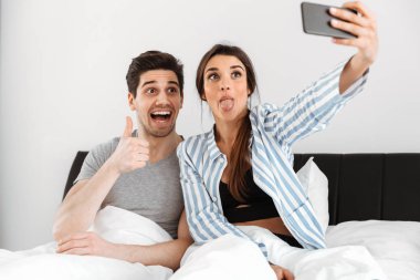 Genç çift yatakta birlikte otururken bir selfie alarak