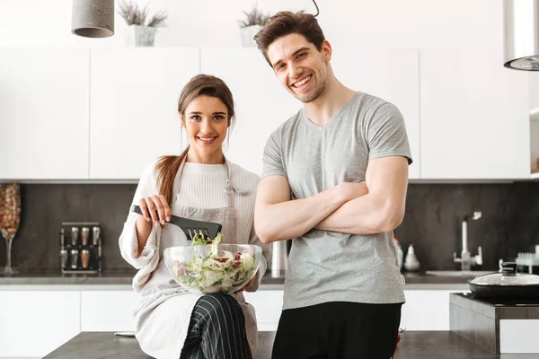 Mutlu bir genç çift yemek salata birlikte mutfak at portresi