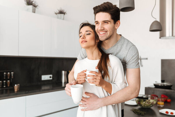 Portrait of a loving young couple drinking coffee at the kitchen at home