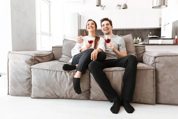 Mutlu genç bir çift gözlük şarap evde bir kanepede rahatlatıcı portresi