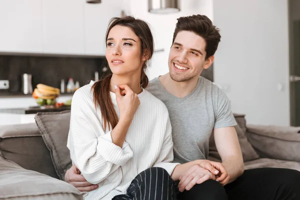 Gülümseyen genç bir çift birlikte evde bir kanepede rahatlatıcı portresi
