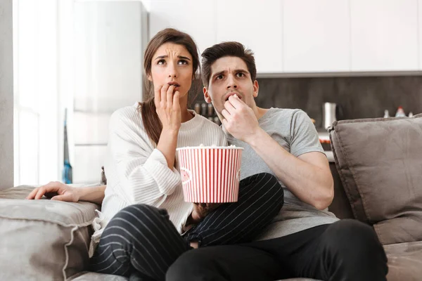 Retrato Una Joven Pareja Asustada Relajándose Sofá Casa Mientras Televisión — Foto de Stock