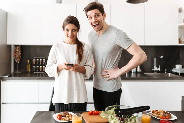 Retrato Jovem Casal Alegre Cozinhando Juntos Enquanto Estão Mesa Cozinha — Fotografia de Stock