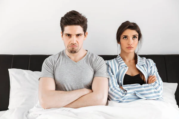 Upset young couple having a conflict while sitting in bed