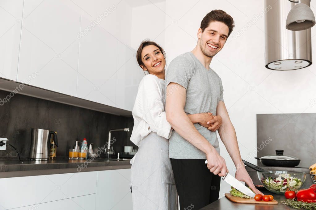 Portrait of a happy young couple cooking together at the kitchen