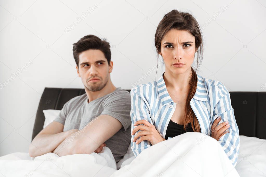 Disappointed young couple having a conflict while sitting in bed