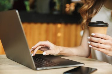 Dizüstü bilgisayarda yazarak ve kahve Kupası'nda tablo açık havada tutan bir kadının yakın çekim