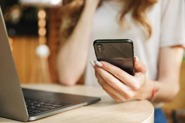 Närbild Kvinnors Handen Håller Mobiltelefon Vid Bordet Med Bärbar Dator — Stockfoto