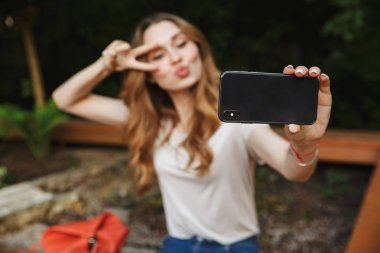 Bir tezgah açık havada üzerinde otururken selfie alarak genç ve güzel kız