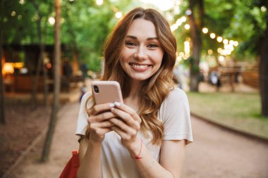 Cep telefonu dururken vasıl belgili tanımlık park holding neşeli genç kız