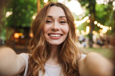 Parkta bir selfie duran uzanmış el ile alarak gülümseyen genç kızın yakın çekim