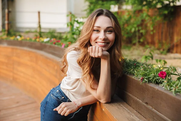 Açık havada duran ise kameraya bakarak rahat kıyafetler içindeki gülümseyen genç kız