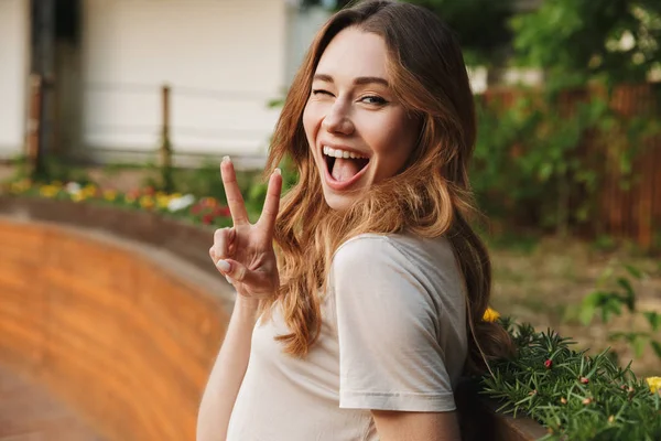 Usměvavá Mladá Dívka Neformálním Oblečení Při Pohledu Fotoaparát Mrkání Stoje — Stock fotografie