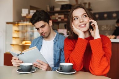 Kafe birlikte, gönüllülük a kitap, kadın cep telefonunda söz adam masadan oldukça genç çift