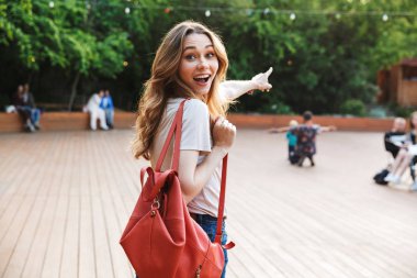 Açık havada yürüyüş ve işaret uzakta sırt çantası ile gülümseyen genç kadın