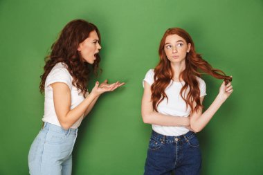 İki Kızıl saçlı kız 20'li yaşlarda mücadele ve kavga yeşil arka plan izole bağırarak