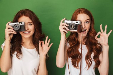 Yeşil arka plan üzerinde izole sembolü retro kamera ve el hareketi iki Kızıl saçlı kadınlar 20'li photopraphing görüntü closeup iyi