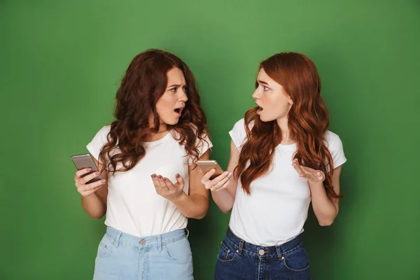 赤い髪と携帯電話を使用して 緑の背景に分離された憤りを表現する つの激怒した女性達の画像 — ストック写真