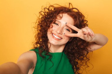 Portre sarı arka plan üzerinde izole bir selfie alarak içinde komik Kızıl saçlı kadın kapatmak