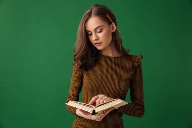 Kitap okuma yeşil arka plan üzerinde izole ayakta şaşırtıcı genç kadın görüntüsünü.