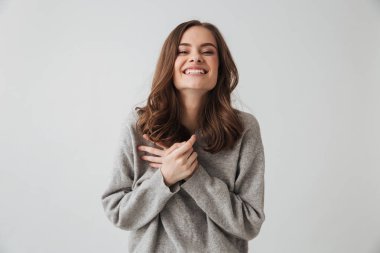 Poz ve gri arka plan üzerinde kameraya bakarak kazaklı esmer kadın gülüyor