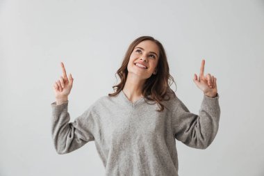 İşaret ve gri arka plan üzerinde ararken kazaklı neşeli esmer kadın görüntüsünü