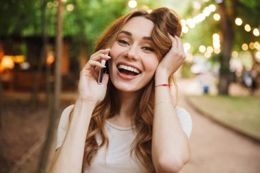 Parkta duran cep telefonu konuşurken neşeli genç kız