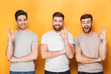 Üç genç heyecanlı adam ok hareket izole sarı arka plan üzerinde gösterilen