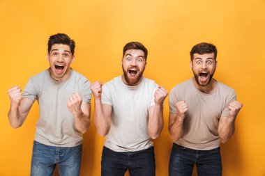 Üç genç mutlu adam başarı birlikte sarı arka plan üzerinde izole kutlama