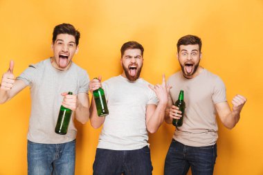 Üç genç adam bira tutarak ve kutlama sarı arka plan üzerinde izole