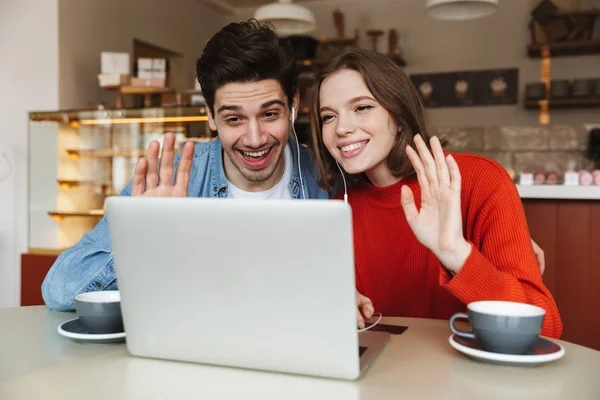 Alegre Pareja Joven Sentados Una Mesa Café Juntos Agitando Las —  Fotos de Stock