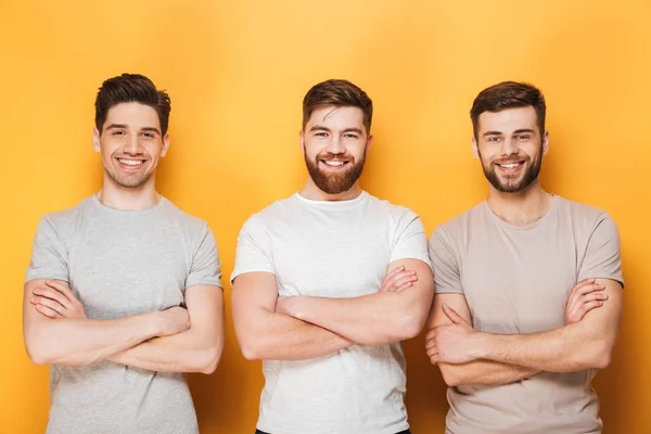 Drei Junge Lächelnde Männer Mit Verschränkten Armen Vor Gelbem Hintergrund — Stockfoto