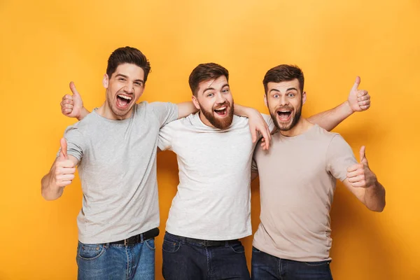 Three Young Excited Men Showing Thumbs Isolated Yellow Background — Stock Photo, Image