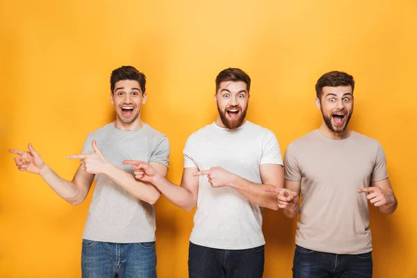 Tres Jóvenes Hombres Alegres Apuntando Hacia Espacio Copia Aislado Sobre — Foto de Stock