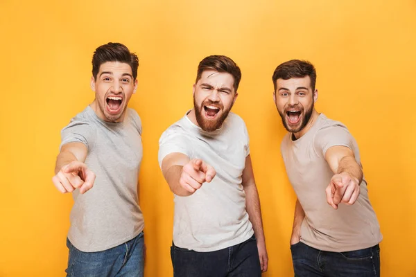 Tres Jóvenes Excitados Apuntando Cámara Gritando Aislados Sobre Fondo Amarillo —  Fotos de Stock