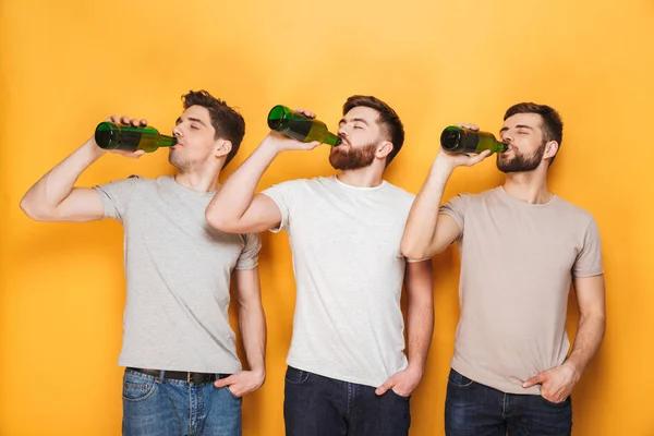 黄色の背景に分離されたビールを飲む三人の若者 — ストック写真
